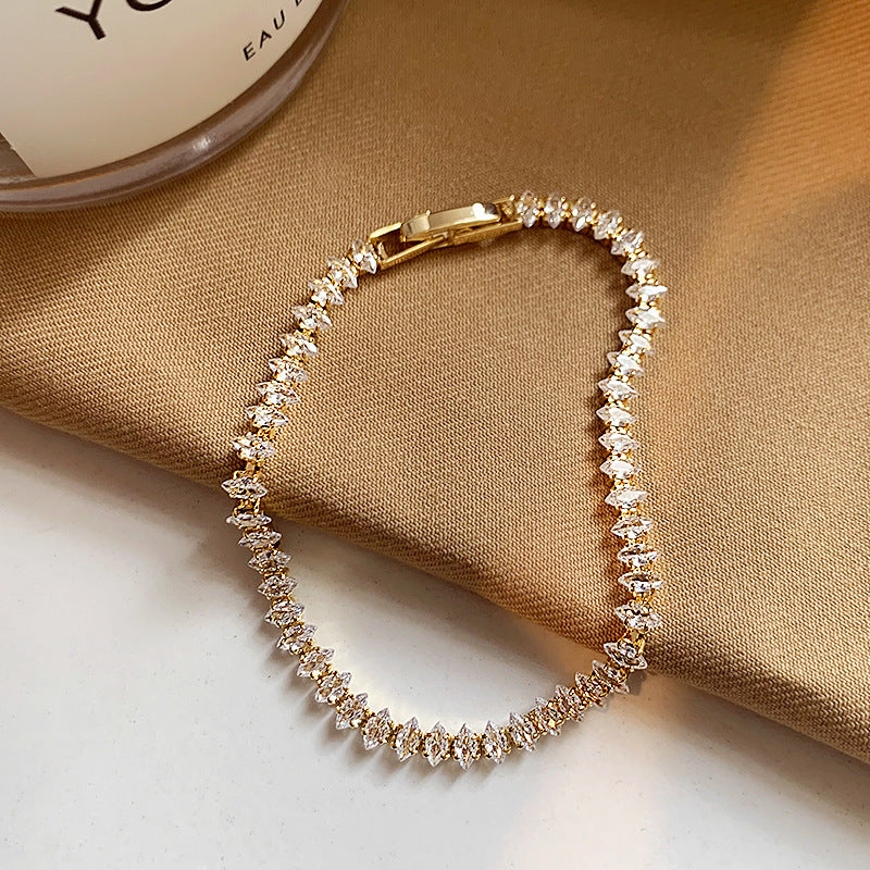 Elegant gold tennis bracelet featuring marquise-cut white cubic zirconia stones in a leaf-style continuous link