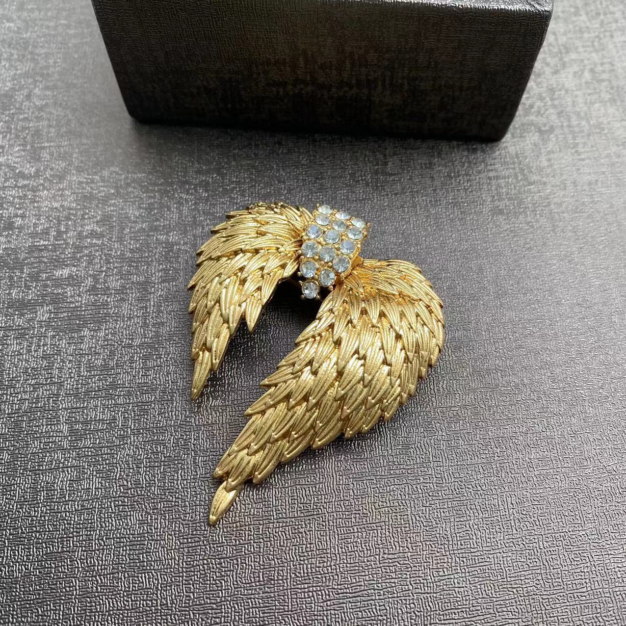 Elegant gold plated angel wing brooch featuring shimmering white cubic zirconia stones in a detailed feather design