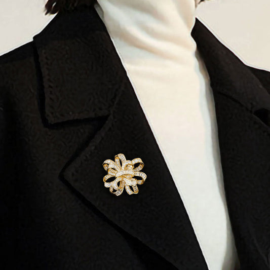 Dainty bowknot brooch with white cubic zirconia ribbon design, available in gold and silver plated finishes