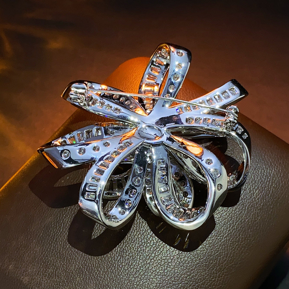 Dainty bowknot brooch with white cubic zirconia ribbon design, available in gold and silver plated finishes