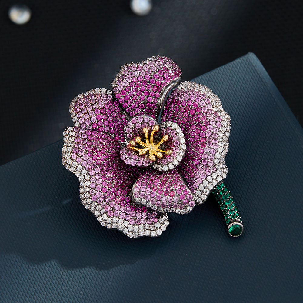 Elegant camellia brooch with purple gradient cubic zirconia petals, a golden stamen, and a green stem