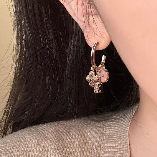 Rose gold huggie hoop earrings featuring a sparkling zirconia pave and a delicate four-leaf clover charm