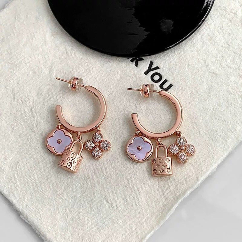 Rose gold huggie hoop earrings featuring a sparkling zirconia pave and a delicate four-leaf clover charm