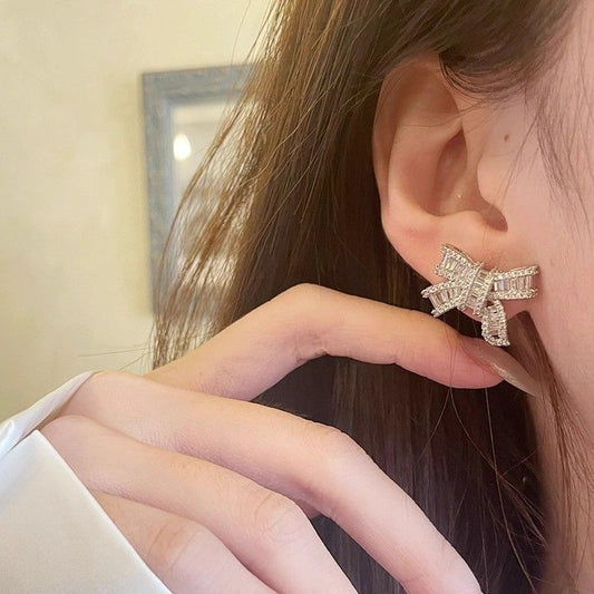 Silver bowknot stud earrings featuring a delicate ribbon design fully set with sparkling clear zirconia stones