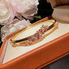 Exquisite 18K gold plated bangle featuring a pink gemstone center, floral motifs, and sparkling zirconia accents