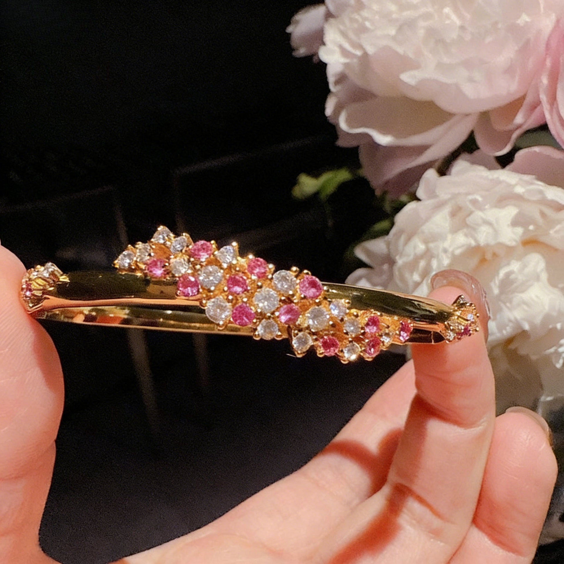 Exquisite 18K gold plated bangle featuring a pink gemstone center, floral motifs, and sparkling zirconia accents