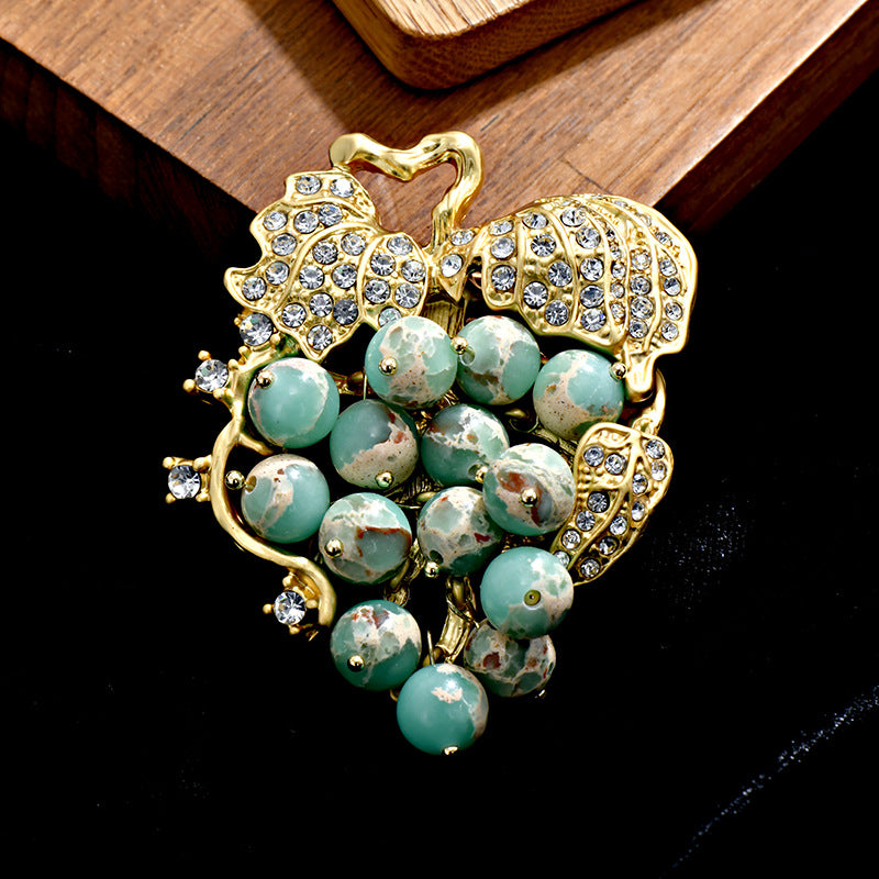 Elegant 18K gold plated grape brooch featuring mint green and purple cubic zirconia stones in a fruit-themed design