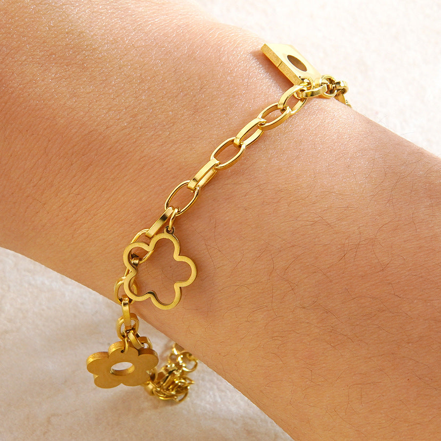 Floral openwork charms engraved lucky tag and geometric drop link chain stainless steel jewelry bracelet in waterproof 18k gold plated finish.