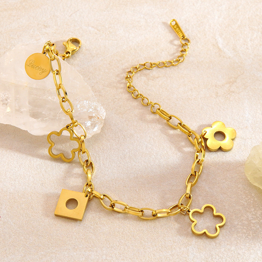 Floral openwork charms engraved lucky tag and geometric drop link chain stainless steel jewelry bracelet in waterproof 18k gold plated finish.