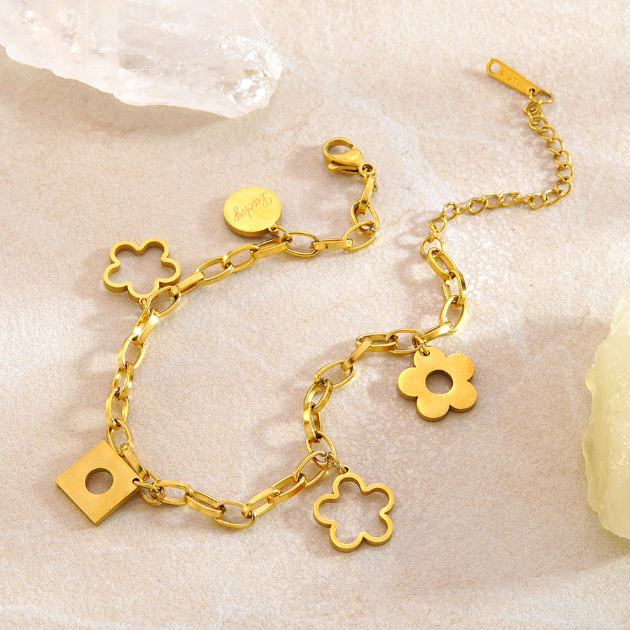 Floral openwork charms engraved lucky tag and geometric drop link chain stainless steel jewelry bracelet in waterproof 18k gold plated finish.