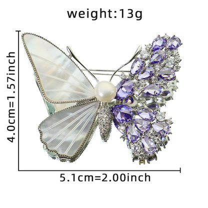 Unique asymmetric butterfly brooch with white mother-of-pearl, purple cubic zirconia clusters, and a central pearl