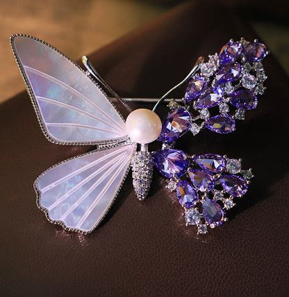 Unique asymmetric butterfly brooch with white mother-of-pearl, purple cubic zirconia clusters, and a central pearl