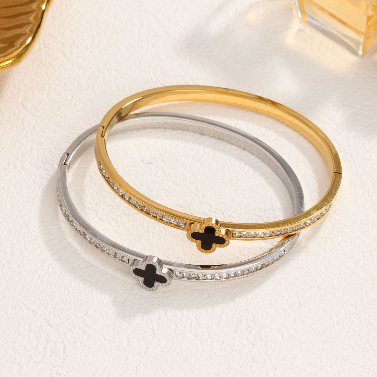 Black enamel clover station and channel-set cubic zirconia hinged cuff bangle in waterproof 18k gold plated stainless steel jewelry.