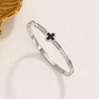 Black enamel clover station and channel-set cubic zirconia hinged cuff bangle in waterproof 18k gold plated stainless steel jewelry.