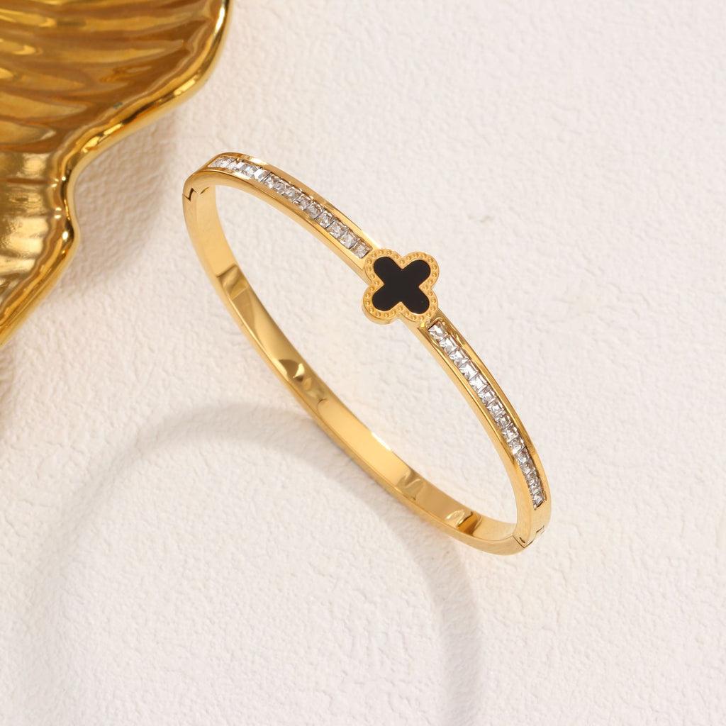Black enamel clover station and channel-set cubic zirconia hinged cuff bangle in waterproof 18k gold plated stainless steel jewelry.