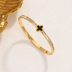 Black enamel clover station and channel-set cubic zirconia hinged cuff bangle in waterproof 18k gold plated stainless steel jewelry.