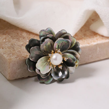 Elegant camellia brooch featuring black mother-of-pearl petals, a central white pearl, and shimmering zirconia accents
