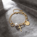 Cross charm pearl bead and engraved quote disc paperclip chain stainless steel jewelry bracelet in waterproof 18k gold plated finish.