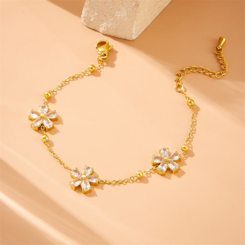 Cubic zirconia cz crystal flower stations and gold bead accents link chain bracelet stainless steel jewelry in waterproof 18k gold plated finish.