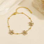 Cubic zirconia cz crystal flower stations and gold bead accents link chain bracelet stainless steel jewelry in waterproof 18k gold plated finish.