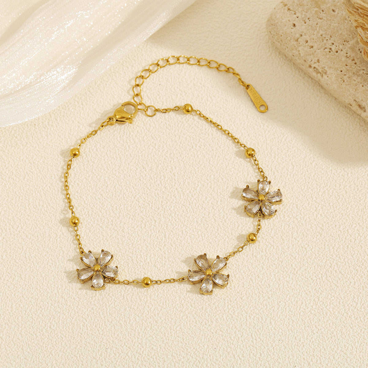 Cubic zirconia cz crystal flower stations and gold bead accents link chain bracelet stainless steel jewelry in waterproof 18k gold plated finish.