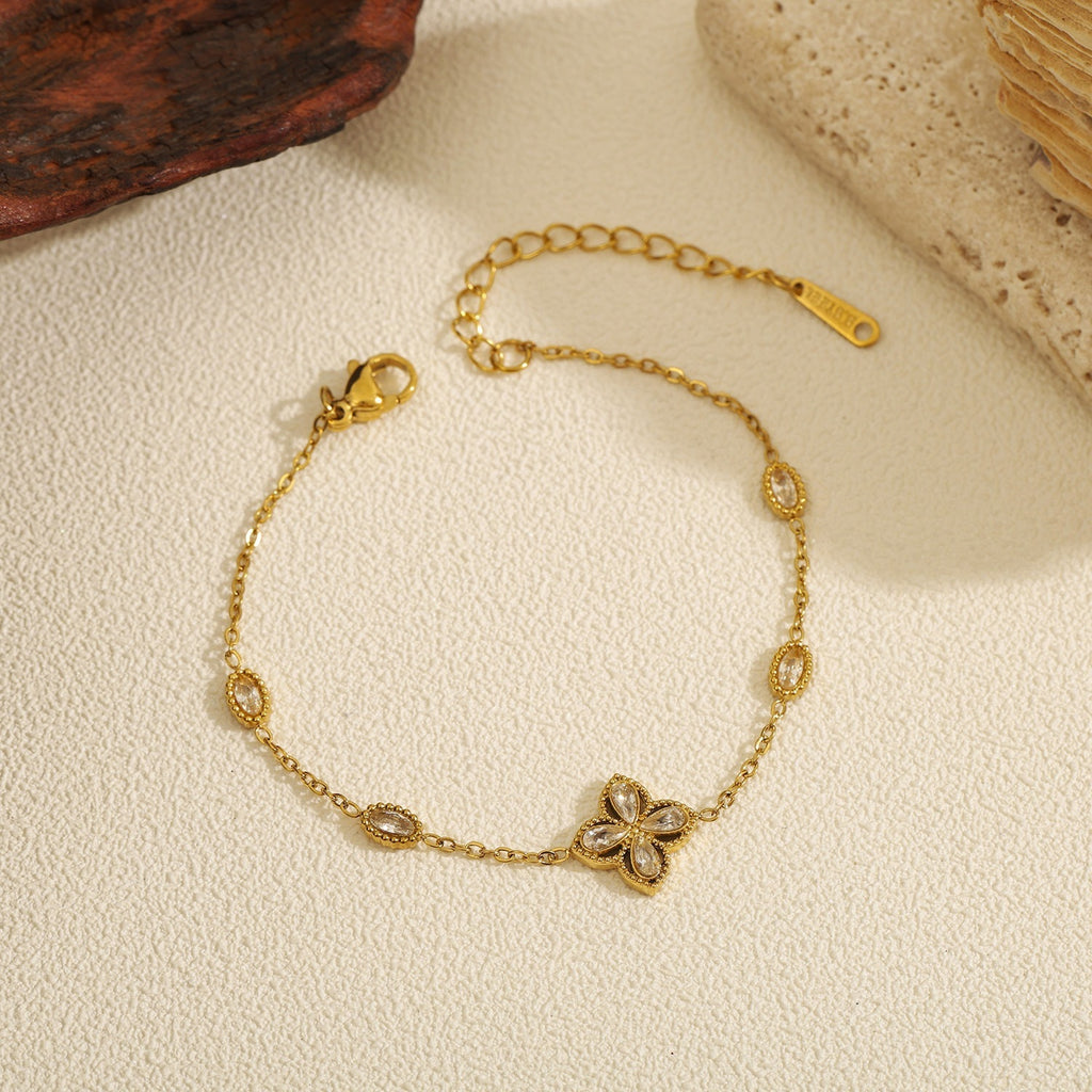 Cubic zirconia cz four petal flower pendant and oval bezel stations cable chain stainless steel jewelry bracelet in waterproof 18k gold plated finish.