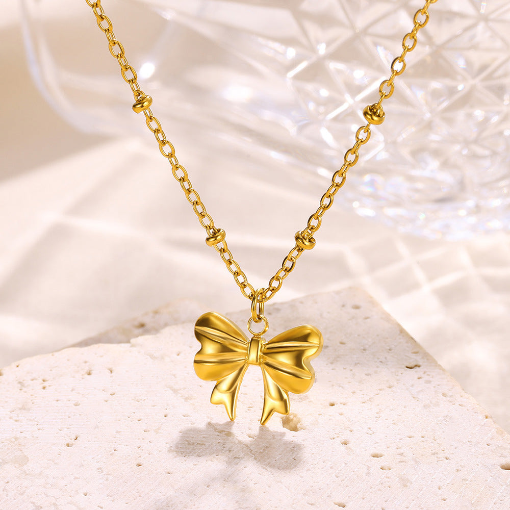 Minimalist gold bow pendant necklace featuring a polished three-dimensional bow on a dainty beaded chain for everyday elegance