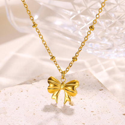 Minimalist gold bow pendant necklace featuring a polished three-dimensional bow on a dainty beaded chain for everyday elegance