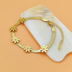 Daisy flower charm stations flat snake link chain stainless steel jewelry bracelet in waterproof 18k gold plated finish.