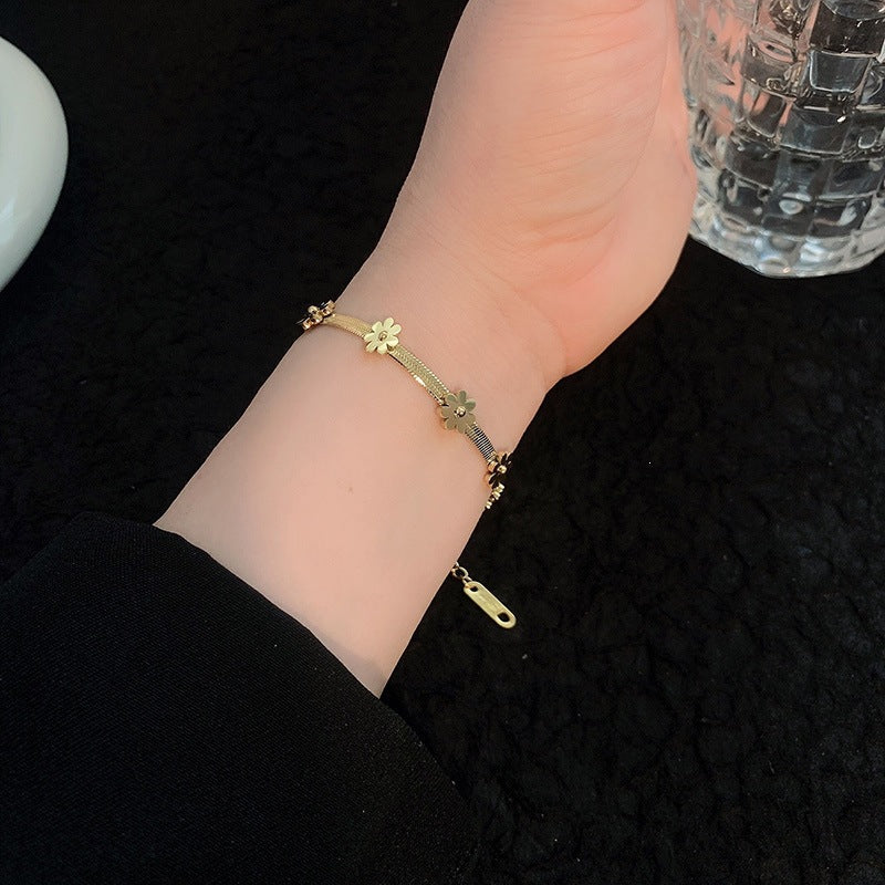 Daisy flower charm stations flat snake link chain stainless steel jewelry bracelet in waterproof 18k gold plated finish.