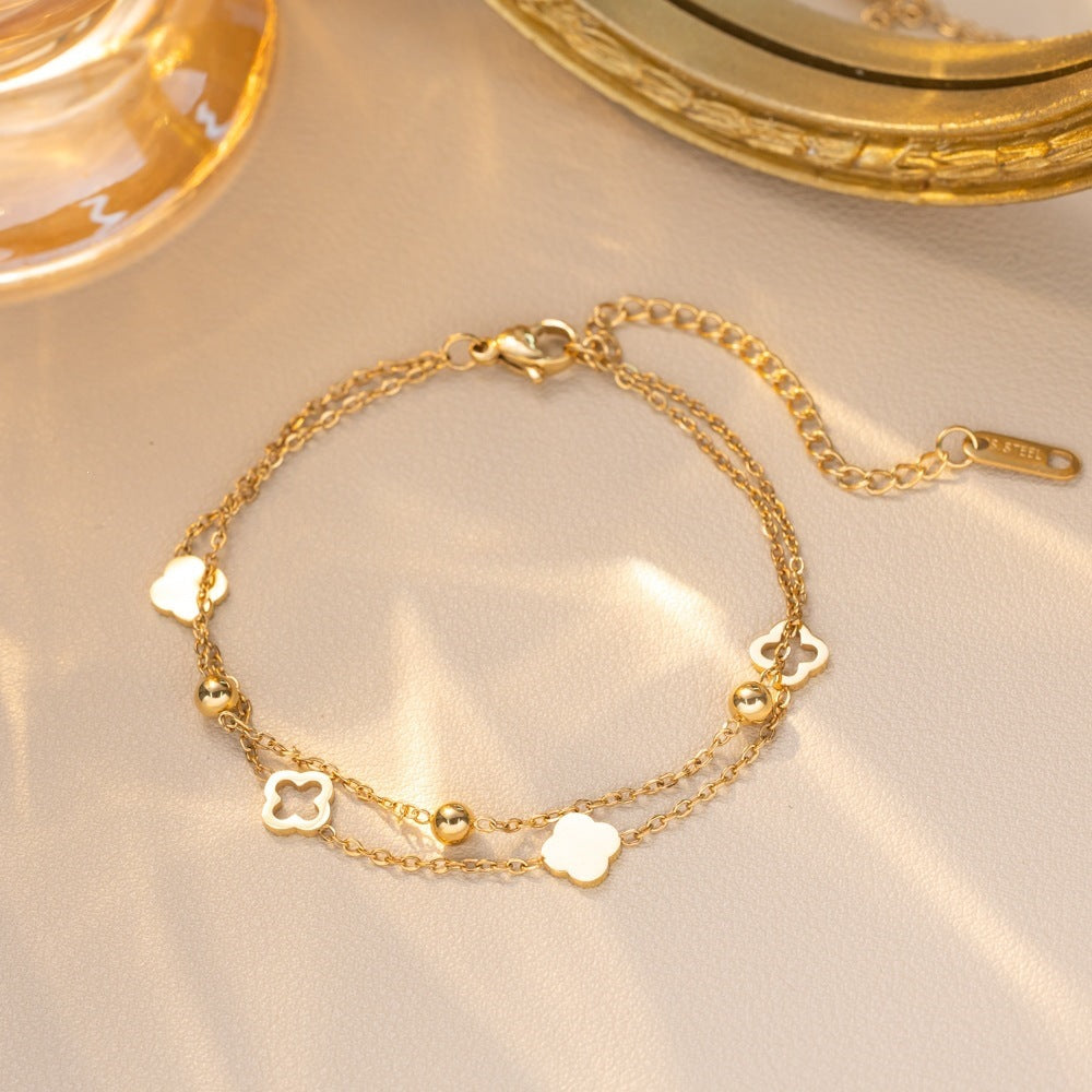 Double strand chain shell clover station and bead accent stainless steel jewelry bracelet in waterproof 18k gold plated finish.