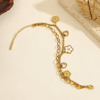 Double layer link chain white shell flower motif and heart cubic zirconia charm stainless steel jewelry bracelet in waterproof 18k gold plated finish.
