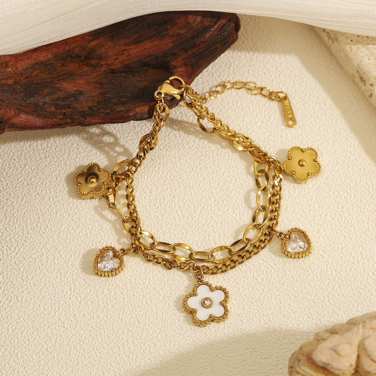 Double layer link chain white shell flower motif and heart cubic zirconia charm stainless steel jewelry bracelet in waterproof 18k gold plated finish.