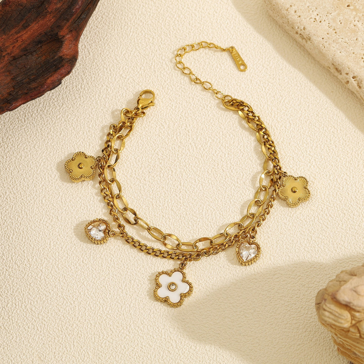 Double layer link chain white shell flower motif and heart cubic zirconia charm stainless steel jewelry bracelet in waterproof 18k gold plated finish.