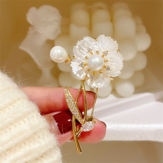 Elegant floral bouquet brooch featuring white cubic zirconia petals and a central pearl in a gold setting