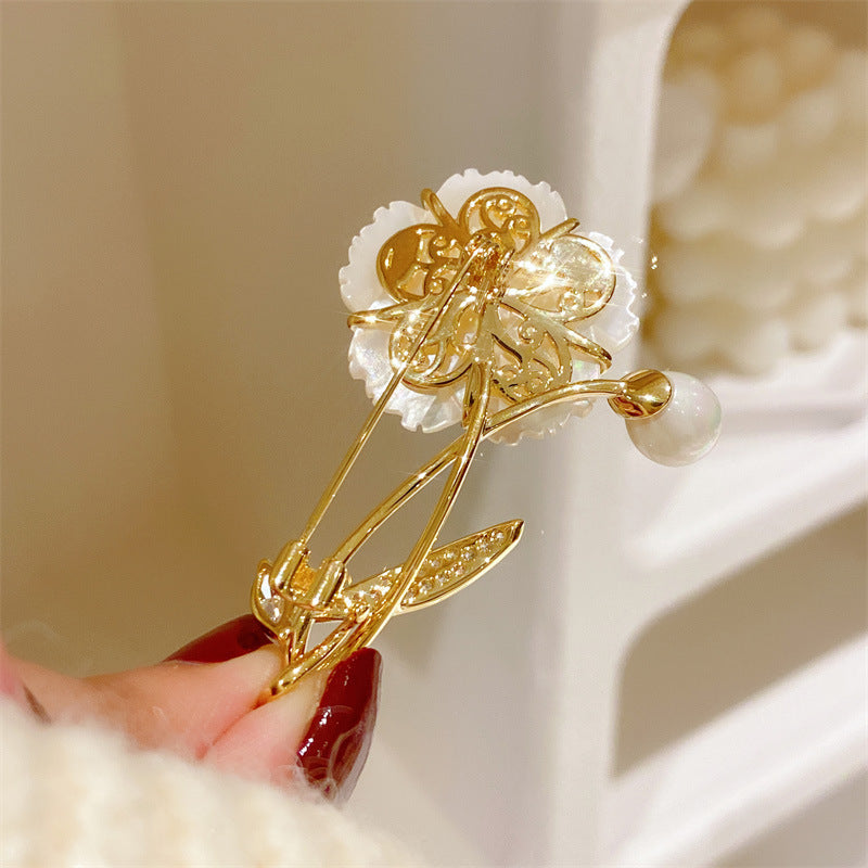 Elegant floral bouquet brooch featuring white cubic zirconia petals and a central pearl in a gold setting