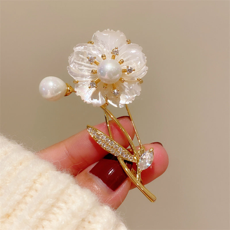 Elegant floral bouquet brooch featuring white cubic zirconia petals and a central pearl in a gold setting