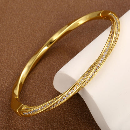 Modern gold bypass wrap bangle featuring dual round halo charms with sparkling white cubic zirconia