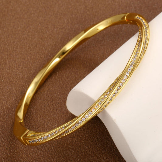 Modern gold bypass wrap bangle featuring dual round halo charms with sparkling white cubic zirconia