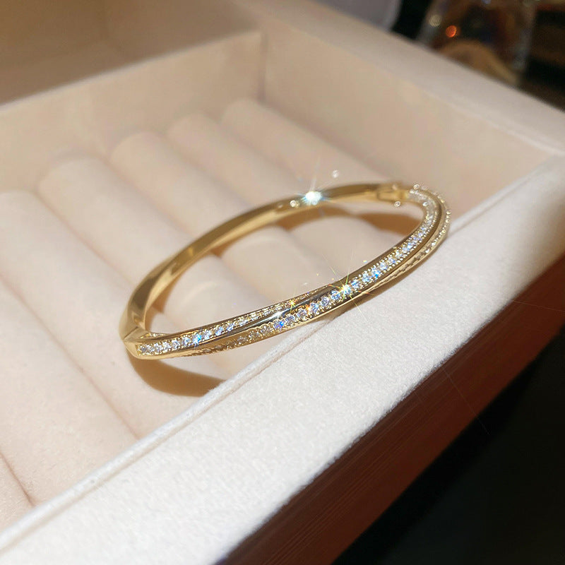 Modern gold bypass wrap bangle featuring dual round halo charms with sparkling white cubic zirconia