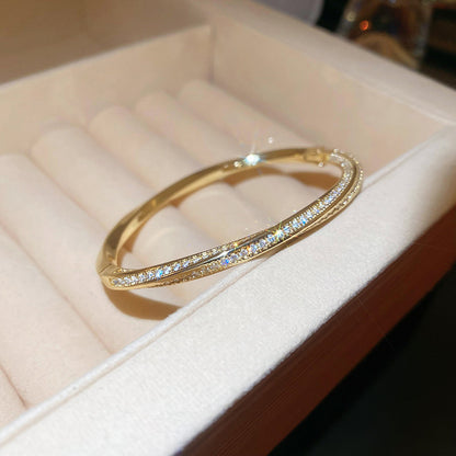 Modern gold bypass wrap bangle featuring dual round halo charms with sparkling white cubic zirconia