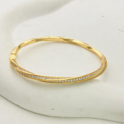 Modern gold bypass wrap bangle featuring dual round halo charms with sparkling white cubic zirconia