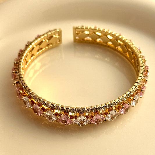 Elegant gold double-layer open bangle with pink gemstone centers and sparkling white zirconia halo