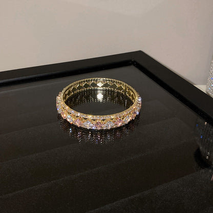 Elegant gold double-layer open bangle with pink gemstone centers and sparkling white zirconia halo