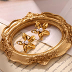 Paired gold flower stud earrings featuring a central white pearl in an elegant blooming petal design
