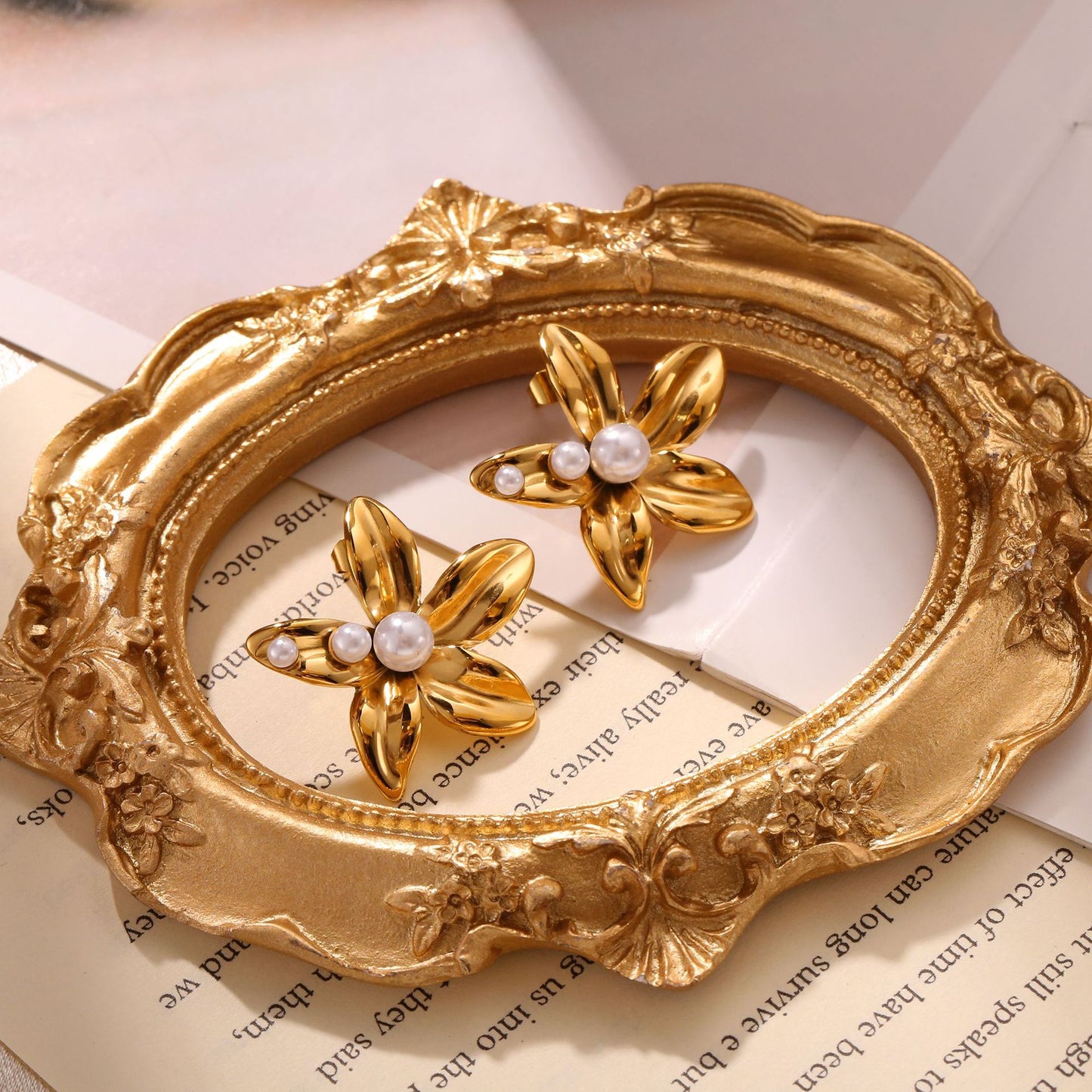 Paired gold flower stud earrings featuring a central white pearl in an elegant blooming petal design