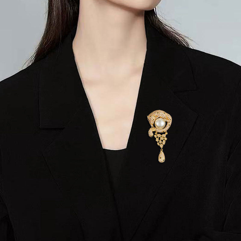 Luxurious gold leopard brooch with sparkling white zirconia and a large central pearl in a wild animal design