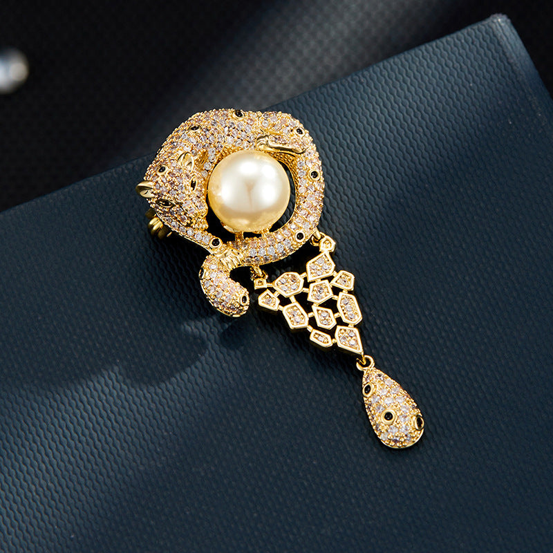 Luxurious gold leopard brooch with sparkling white zirconia and a large central pearl in a wild animal design