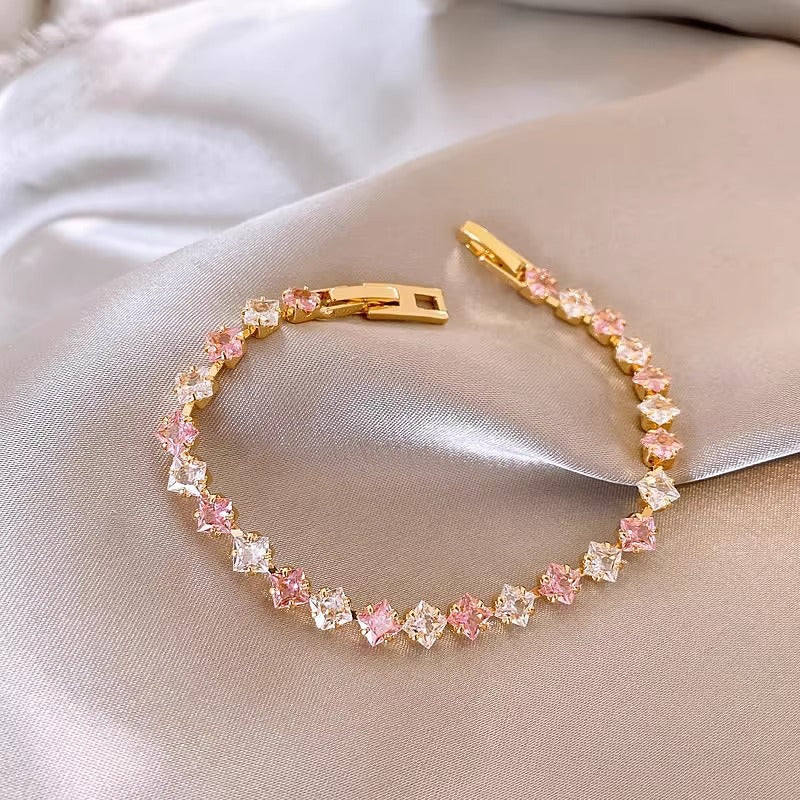 Classic gold tennis bracelet featuring a continuous line of sparkling pink cubic zirconia stones