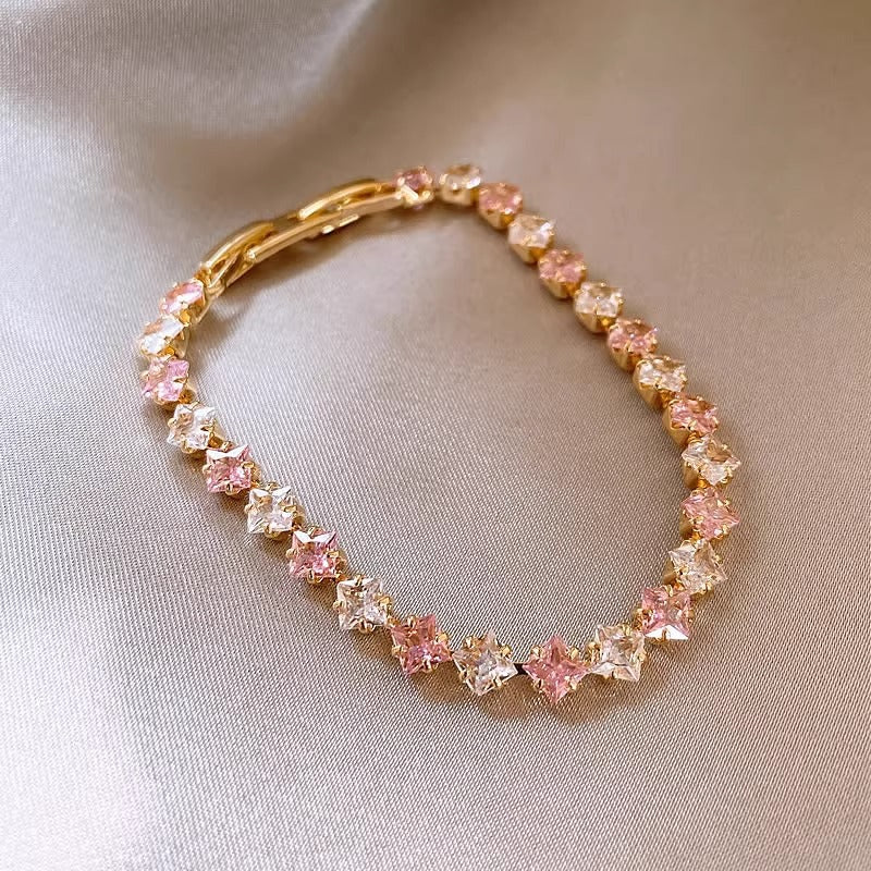 Classic gold tennis bracelet featuring a continuous line of sparkling pink cubic zirconia stones